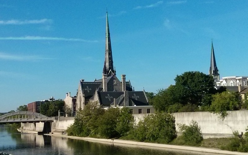 Church spires beside the Grand River in Galt, Cambridge, under a blue sky