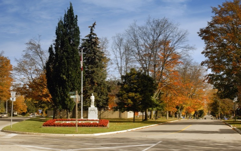 Tree-lined street with autumn colour and a statue in a flower bed in Elmira, Ontario