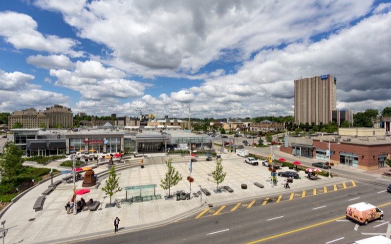 Waterloo Public Square and surrounding Uptown buildings under a blue sky with clouds