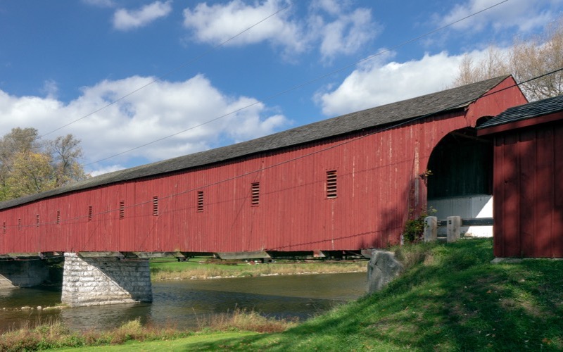 The red West Montrose Covered Bridge over the Grand River under blue sky